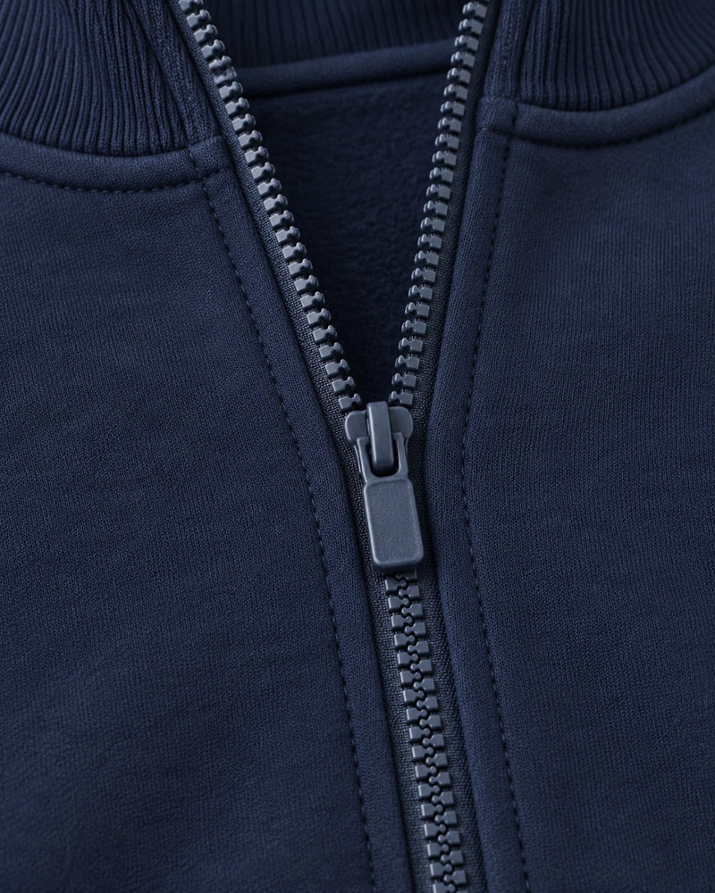 Close-up of the centre-front zipper on the navy Aombe Sweat Jacket, showing teeth, tape and topstitching